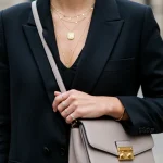 Woman in stylish outfit with statement necklace and elegant handbag, demonstrating elevated accessorising.